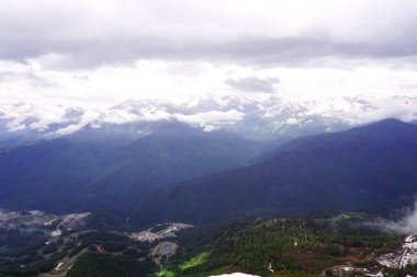 Yüksek dağ manzarası, mavi gökyüzü, bulutlar ve sis.