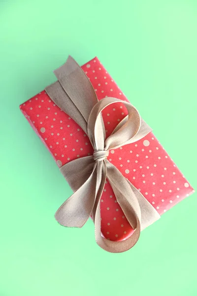 Roter Geschenkkarton mit Goldschleife isoliert auf grünem Hintergrund. — Stockfoto