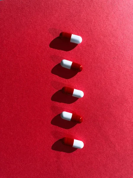 Red and white pills on red textured background. — Stock Photo, Image