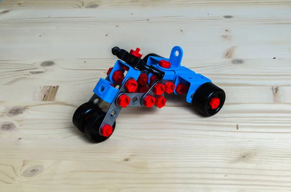 Tahta arka planda plastik Meccano ile yapılmış üç tekerlekli motosiklet.