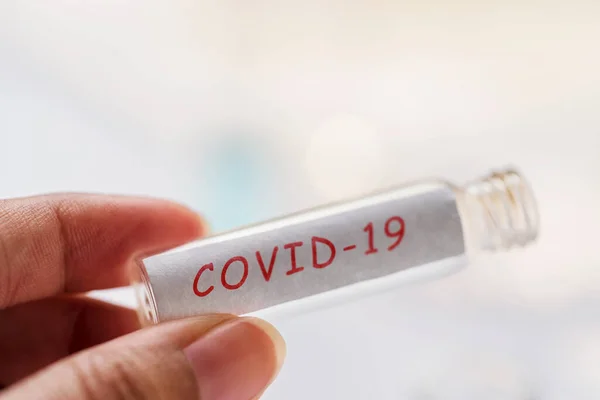 Corona Virus Background. Person holding blank glass vile for collecting blood sample of Covid-19 affected patient. Concept for novel chinese coronavirus outbreak in India, pandemic medical health risk.