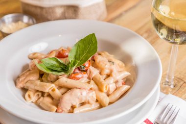 Penis pasta with tomato sauce, tomatoes decorated with Basil on a wooden table