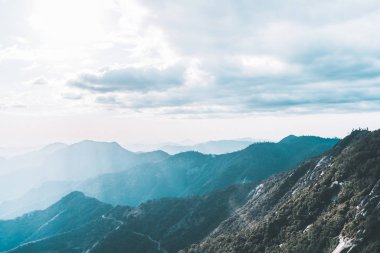 Sequoia Ulusal Parkı 'ndaki Moro Kayası' ndan muhteşem manzara. Arka planda sisli dağlar ve ufku aydınlatan güzel güneş ışınları var.