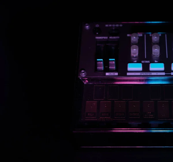 Малый аналоговый fm модуляционный синтезатор крупным планом, выбранный фокус, с ручками и фэйдерами, с эффектами арпеджиатора и секвенсора, цветное освещение, черный фон, копировальная паста, концепция музыкального продюсера — стоковое фото