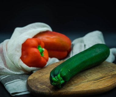 Kırmızı biber ve yanında kabak olan ip torbaları. Tahta tahtada, siyah arka planda, sıfır atık kavramı..