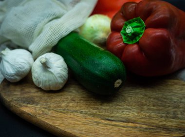 Kırmızı biber, soğan, sarımsak ve kabak, tahta bir tahta üzerinde, siyah arkaplan, sıfır atık kavramı