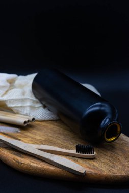 Pamuk bir torba, alüminyum şişe, bambu diş fırçası ve ahşap bir masada bambu pipetle tekrar kullanılabilir çevre dostu eşyalar. Sıfır atık.