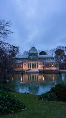Madrid El Retiro Parkı 'ndaki göl manzarası ve Kristal Saray, bulutlu bir gün, romantik tarz pavyon, seyahat konsepti.