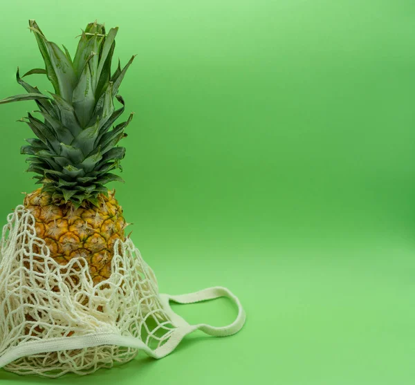 Piña en bolsa de algodón orgánico situada a la izquierda de la imagen, con espacio para texto a la derecha. Concepto alimentario saludable y ecológico. Residuos cero . — Foto de Stock