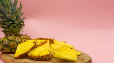 Pembe arka planda izole edilmiş bir tahta üzerinde dilimlenmiş ananas. Mesaj için sağda boşluk var. Sağlıklı ve ekolojik gıda kavramı.