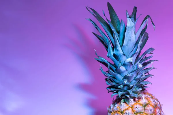 Piña iluminada con destello de color aislado sobre un fondo rosa, situada en el lado derecho de la imagen con espacio a la izquierda para el texto. Concepto de verano . — Foto de Stock