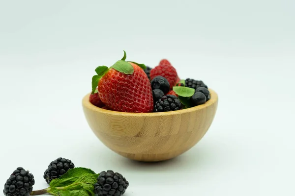 Kilátás egy fából készült tál tele eper, szeder, málna és áfonya. Fehér háttér. Egészséges élelmiszer-koncepció. — Stock Fotó