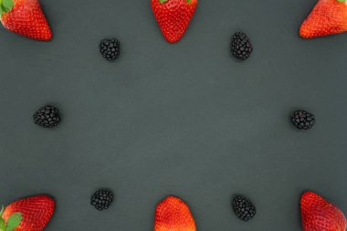 Karatahta arka planında çilek ve böğürtlen çerçevesi, ortasında yazı için yer var. Sağlıklı gıda konsepti.