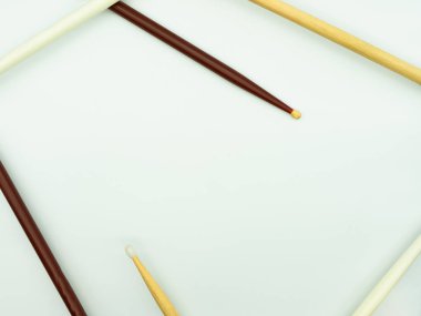 Top view of drumsticks on white background forming a frame, with space in the middle of the image for text Concept of musical instruments.