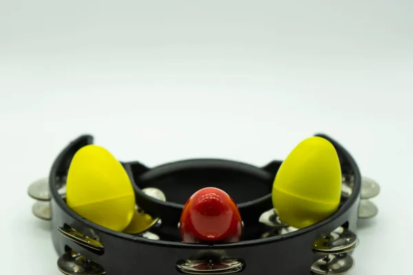 Black tambourine with egg shakers on a white background. Space above for text. Concept percussion instruments.