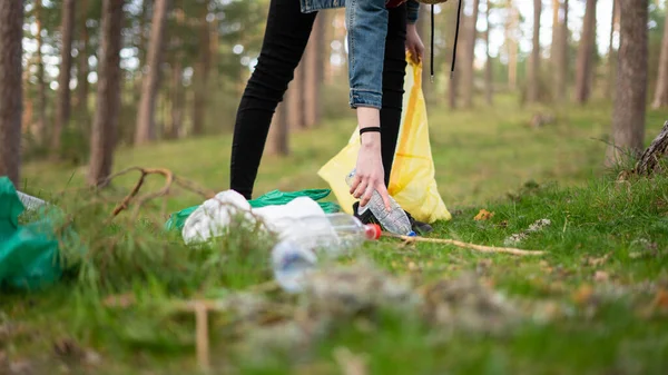 Ormanda plastik kazık çakan genç bir kızın yerden görünüşü. Sürdürülebilirlik kavramı.