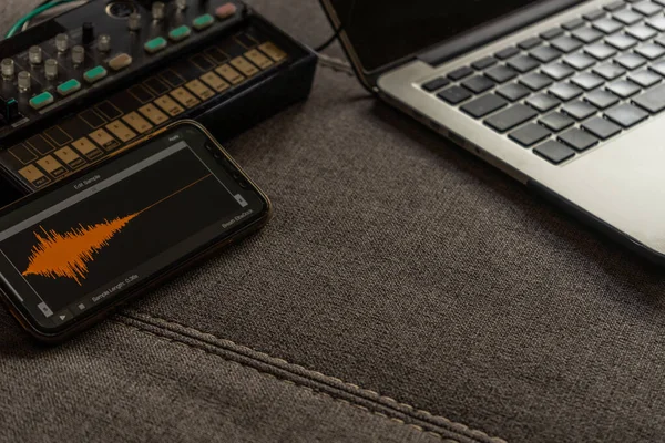 Bilgisayarın, küçük sentezleyicinin ve ses düzenleme uygulaması olan akıllı telefonun görüntüsünü kapat Müzik kavramı.