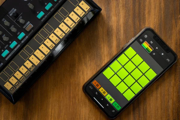 Top view of fm synthesizer and smartphone with drum machine application on a wooden table Electronic music concept.