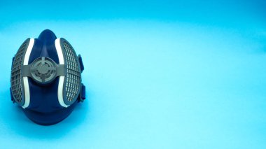 Mavi arkaplandaki izole edilmiş koronavirüs maskesinin üst görüntüsü, görüntünün solunda yer alan sağdaki yazı için yer var. Virüs kavramı. Covid 19.