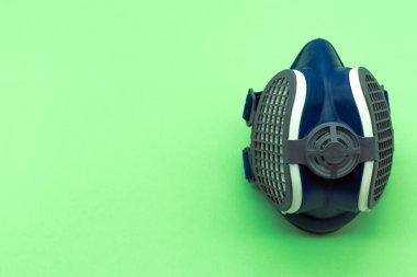 Yeşil arkaplandaki izole edilmiş koronavirüs maskesinin üst görüntüsü, resmin sağında ve solunda yazı için yer var. Virüs konsepti. Covid 19.
