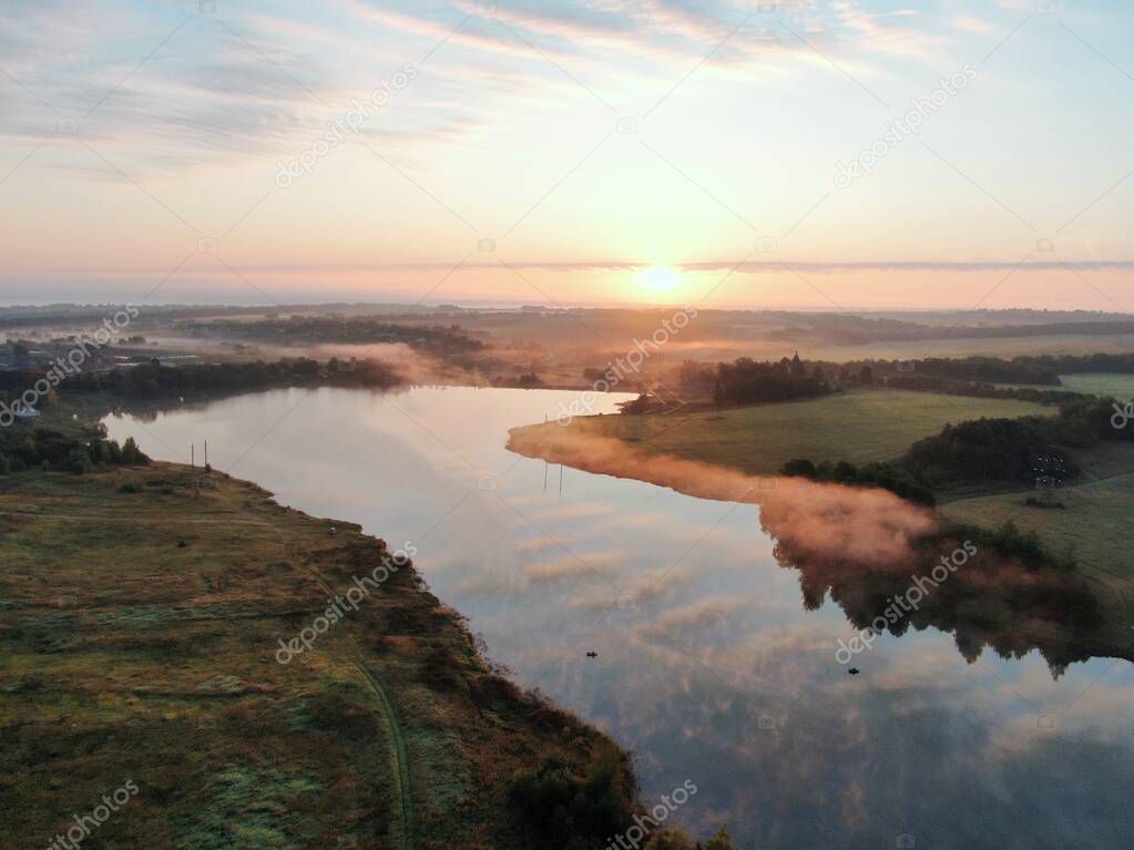 Aerial view of sunset river. Drone flying over the river at dawn in the fall. Fog over water.