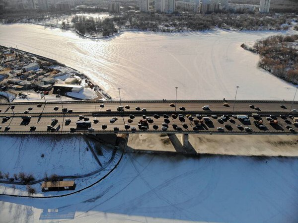 Panoramic aerial view on the Leningradsky Highway on a cold sunny day in winter. Beautiful urban landscape river covered with ice. Cars on the bridge.Drone shot.