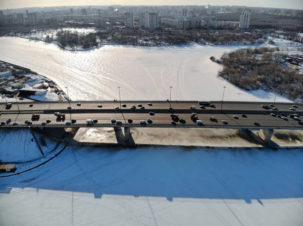 Panorama-Luftaufnahme auf dem Leningradsky Highway an einem kalten, sonnigen Tag im Winter. schöne Stadtlandschaft Fluss mit Eis bedeckt. Autos auf der Brücke beschossen. — Stockfoto