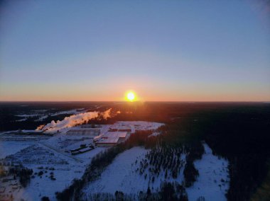 Soğuk ve açık bir sabahta kış gündoğumunun havadan görünüşü. Ormanın ve tarlaların karlı manzarasının panoramik görüntüsü