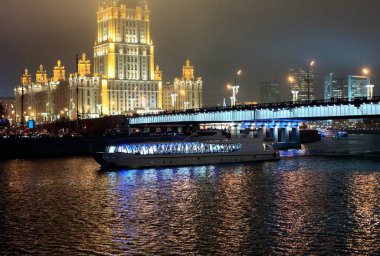 Şehir manzarasının güzel bir manzarası. Nehirdeki yolcu gemisi neon ışıklarıyla köprünün altından geçiyor.