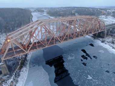 Aerial view, drone shot railway bridge over freezing river. Beautiful panoramic landscape of winter nature
