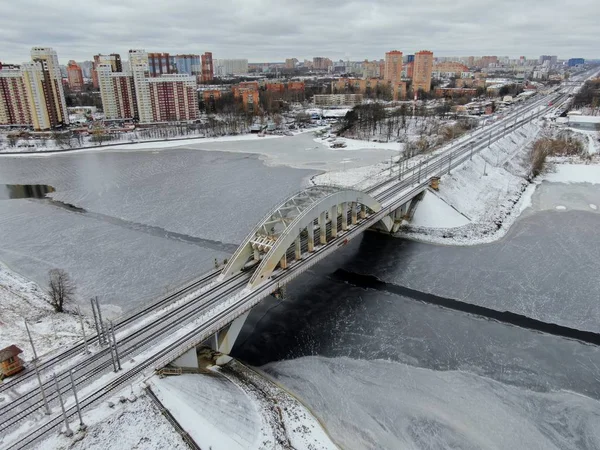 Aerial view beautiful urban landscape railway bridge over freezing river from drone