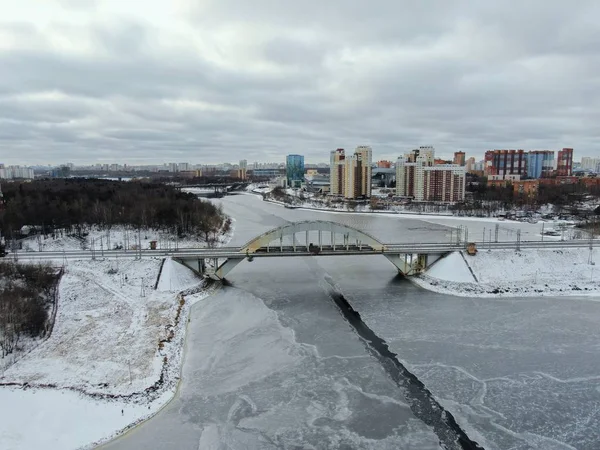 Aerial view beautiful urban landscape railway bridge over freezing river from drone