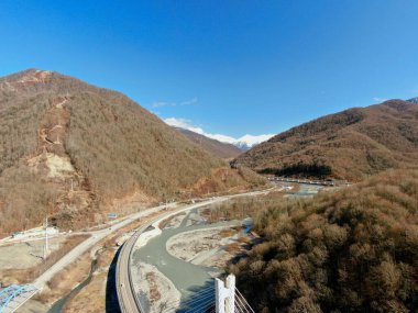 Hava manzaralı açık bir günde, bir dağ geçidinde uzanan güzel bir minibüs köprüsü. İnsansız hava aracından dağ manzarasının güzel manzarası