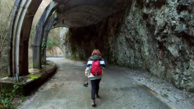 Genç bir fotoğrafçı kız sırt çantasıyla kayalık bir vadide güzel bir dağ yolunda seyahat ediyor. Dağlardaki güzel tüneller ve mağaralar. Dağlarda ve nehirlerde yürüyüş yapmak.