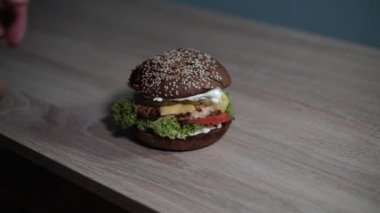 Adam masadan bir hamburger alıyor.