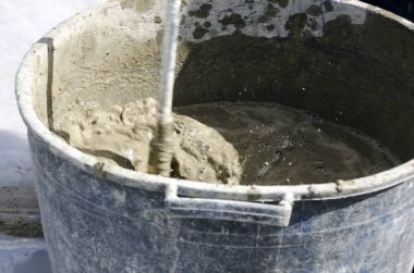 bir çatı yenileme için bir bina yerinde çimento atar işçi