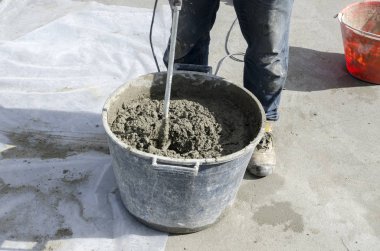 bir çatı yenileme için bir bina yerinde çimento atar işçi