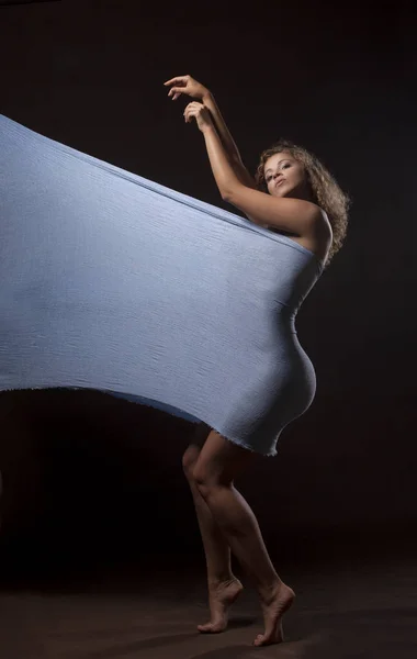 Красивая молодая девушка танцует с голубой тканью — стоковое фото