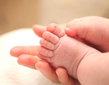 Küçük yeni doğan bebek ayak kadın elinde.