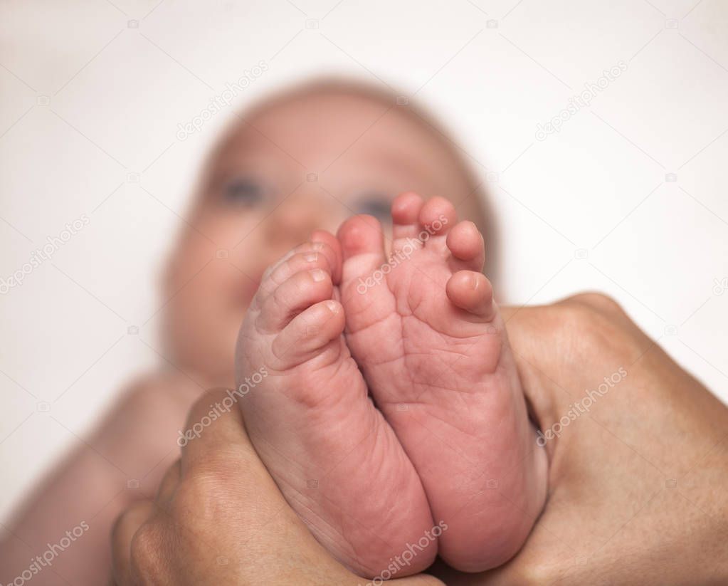 Tiny newborn baby foot in female hands.