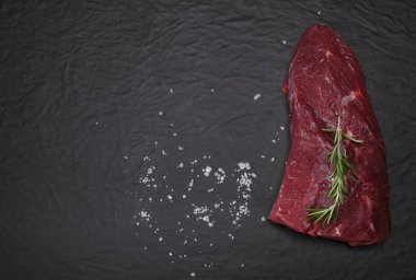 Bir kesme tahtası biberiye ve baharatlar ile ham sığır eti biftek.