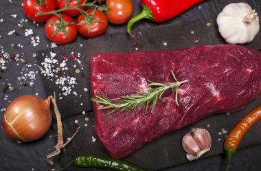 Bir kesme tahtası biberiye ve baharatlar ile ham sığır eti biftek.