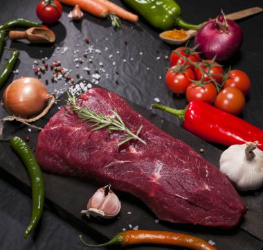 Bir kesme tahtası biberiye ve baharatlar ile ham sığır eti biftek.