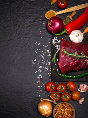 Bir kesme tahtası biberiye ve baharatlar ile ham sığır eti biftek.