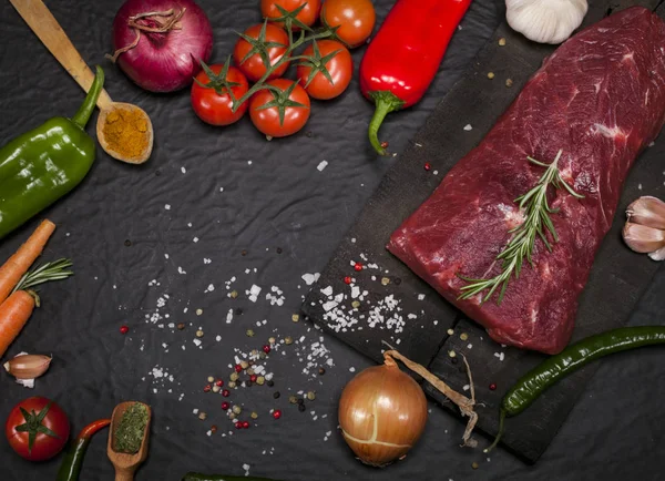 Rauwe biefstuk op een snijplank met rozemarijn en specerijen. — Stockfoto
