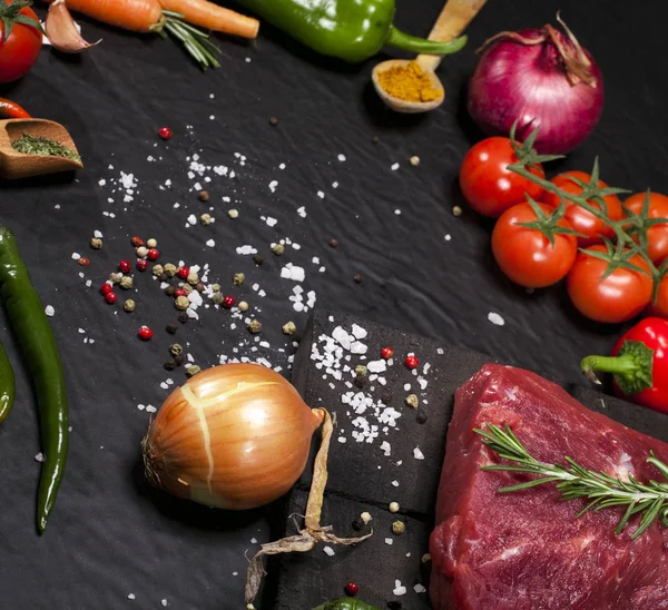 Rauwe biefstuk op een snijplank met rozemarijn en specerijen. — Stockfoto