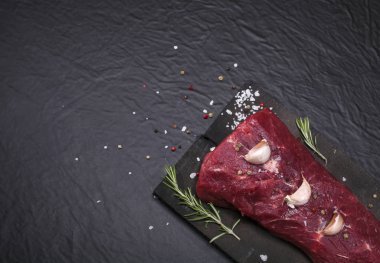 Bir kesme tahtası biberiye ve baharatlar ile ham sığır eti biftek.