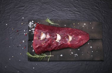 Bir kesme tahtası biberiye ve baharatlar ile ham sığır eti biftek.