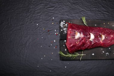 Bir kesme tahtası biberiye ve baharatlar ile ham sığır eti biftek.