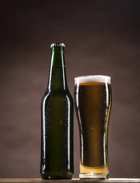 Beer bottle and mug on brown background — Stock Photo, Image